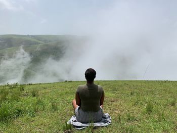 Rear view of woman sitting on mountain peak