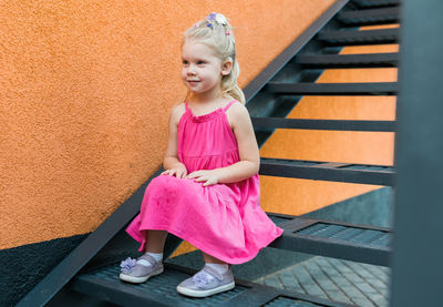 Portrait of young woman standing against wall