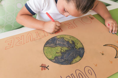 Girl writing on cardboard paper at home