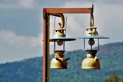 Low angle view of lighting equipment hanging by pole against sky