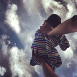 Low angle view of father with daughter against sky