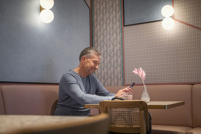 Full length of man sitting on table in illuminated room