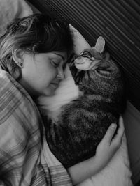 Directly above shot of woman and cat sleeping on bed at home