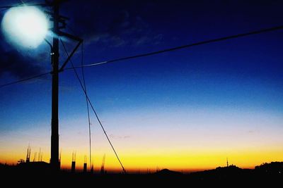 Low angle view of silhouette electricity pylon against sky at sunset