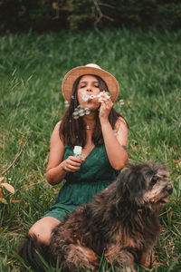 Woman blowing bubbles by dog on lawn