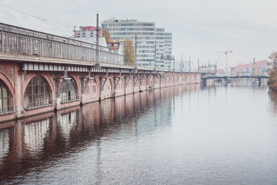 Bridge over river in city against sky