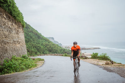 Rear view of man riding bicycle on road