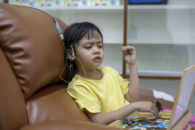 Rear view of girl sitting on table