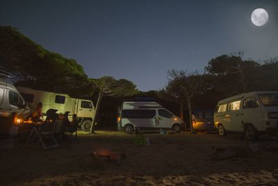 People on illuminated field against sky at night