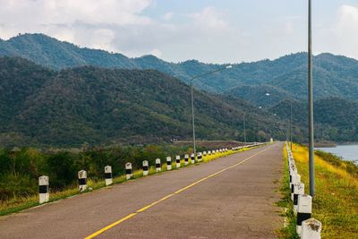 Road by mountains against sky