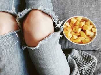 High angle view of legs by salads on sofa