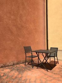 Empty chairs and table against wall