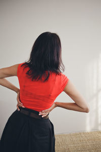 Rear view of woman standing against wall at home