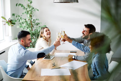 Smiling coworkers toasting drinks at table