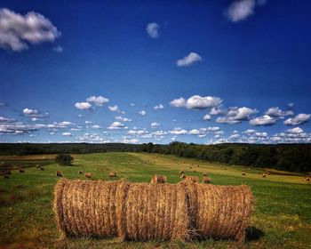 Hay bales on field against sky