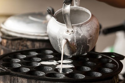 Close-up of pouring batter from kettle in container
