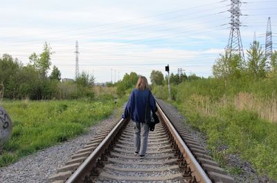 Rear view of man walking on railroad track