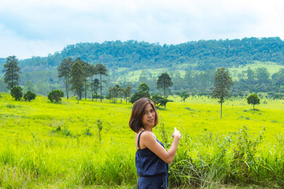Side view portrait of woman standing on green landscape