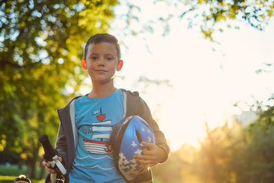 Portrait of boy standing against trees