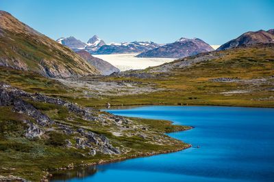 Scenic view of lake and mountains against blue sky