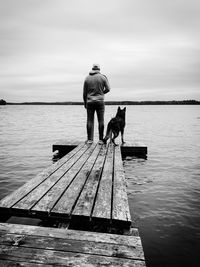 Man with dog on pier against sky