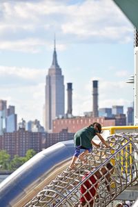 Girl climbing on outdoor play equipment against sky