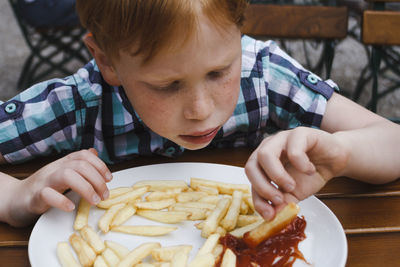 Close-up of boy having french fries at table