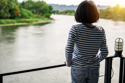 Rear view of woman standing against lake