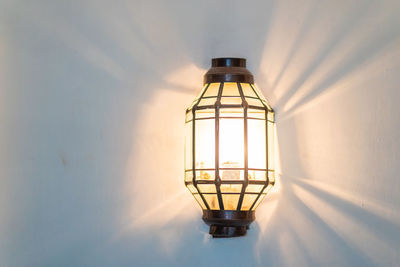 Low angle view of illuminated lamp on wall