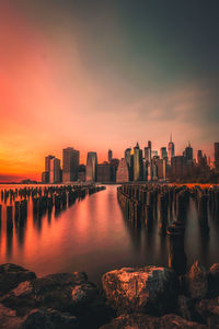 Scenic view of river by buildings against sky during sunset