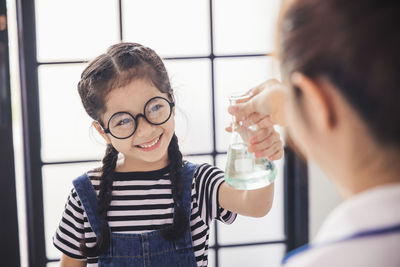 Smiling girl wearing glasses holding flask in laboratory