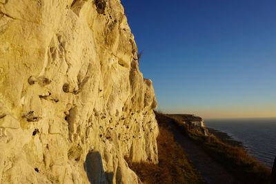 Rock formations in sea against clear blue sky