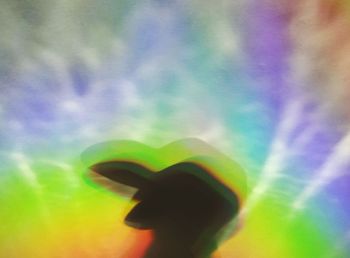 Defocused image of silhouette man standing against rainbow