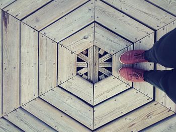 Low section of person standing on hexagon shape wooden floor