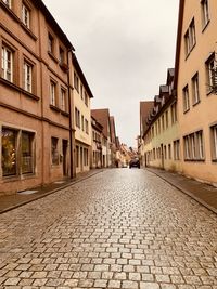 Footpath amidst buildings against sky