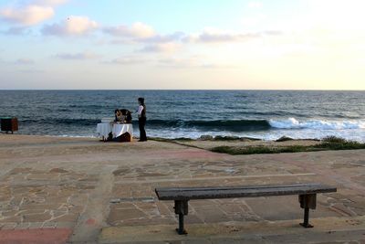 People on table by sea against sky