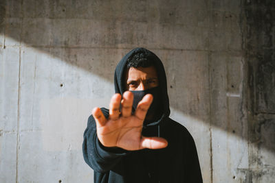Portrait of man holding smart phone while standing against wall