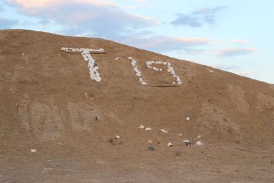 Low angle view of text on sand at beach against sky