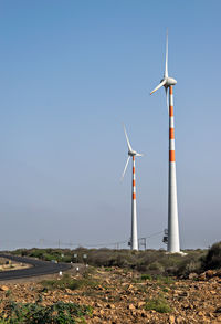 Windmills on field against clear sky