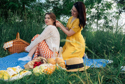 Side view of young woman sitting on field