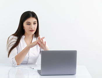 Young woman using laptop against white background
