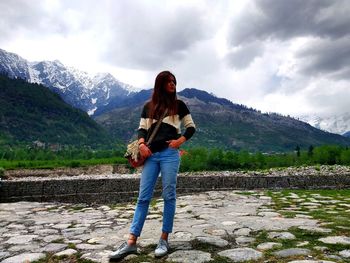 Full length of woman standing on mountain against sky