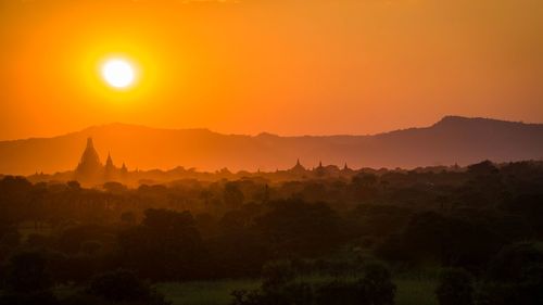 Scenic view of silhouette mountains against orange sky