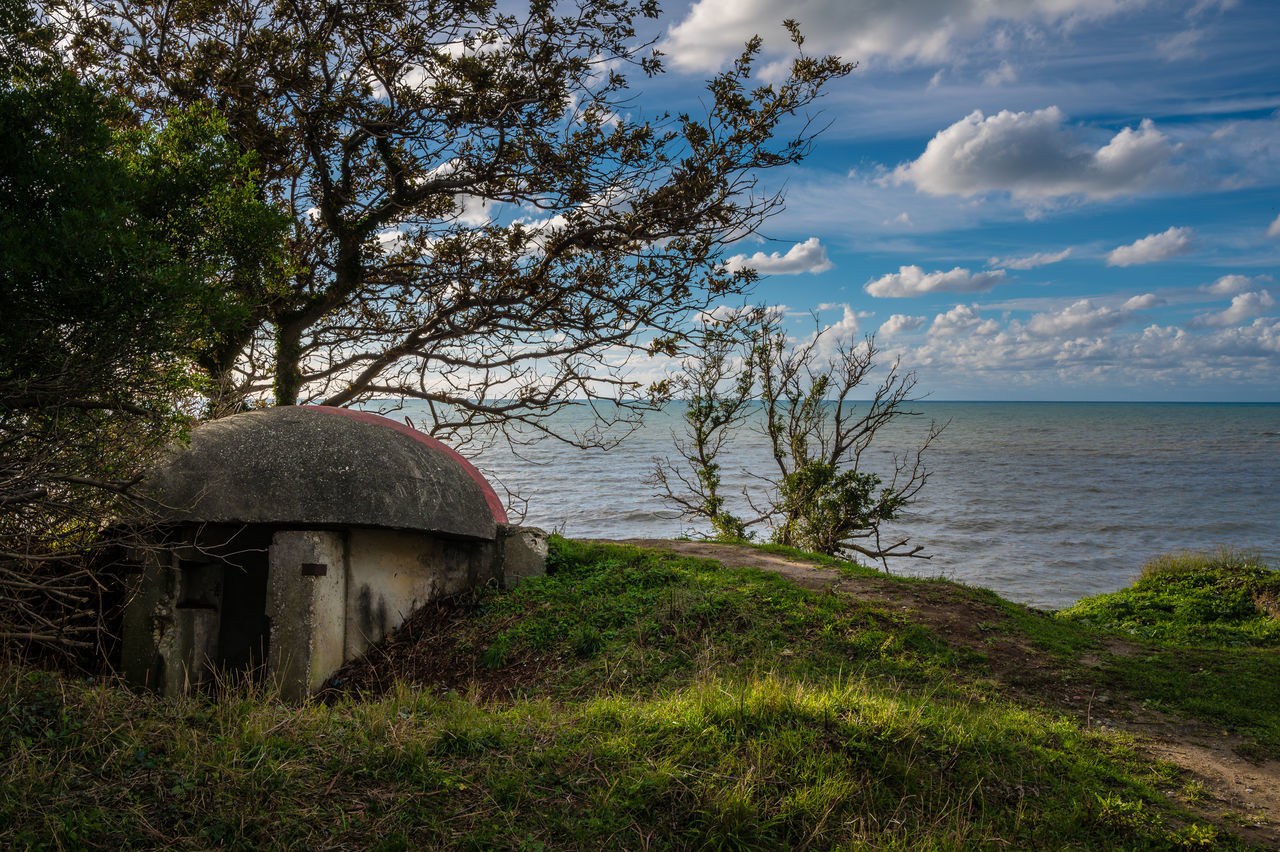 plant, sky, water, tree, nature, land, sea, architecture, cloud, scenics - nature, beauty in nature, rural area, built structure, no people, beach, grass, tranquility, building exterior, tranquil scene, building, landscape, horizon over water, day, outdoors, travel destinations, coast, hill, horizon, environment, growth, hut, house, tourism, non-urban scene