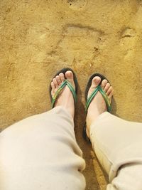 Low section of man standing on sand