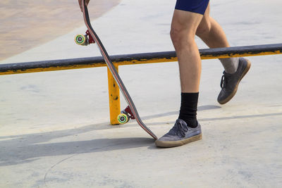 Low section of man with skateboard on footpath