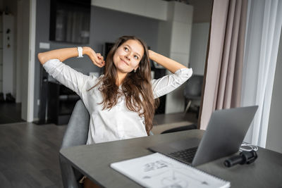 Portrait of young woman using laptop at table