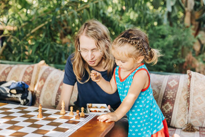 Father and daughter playing chess on table