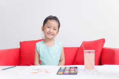 Portrait of smiling girl sitting on table