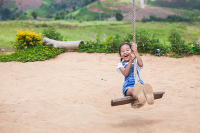 Full length of girl swinging at playground